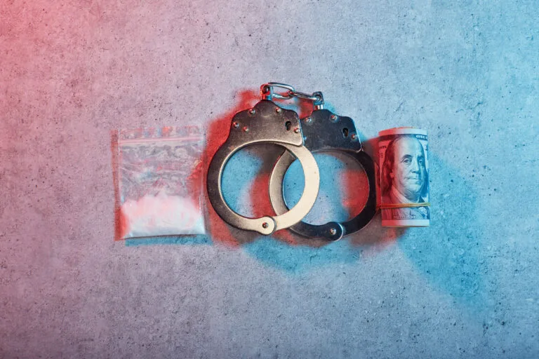 Handcuffs and roll of American one hundred dollar banknotes
